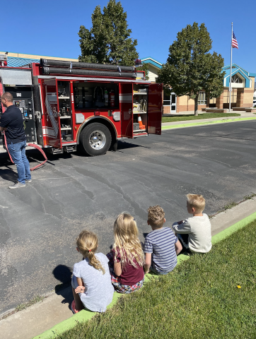 fire truck with children sitting on curb