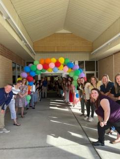 Teachers welcoming students under balloon arch